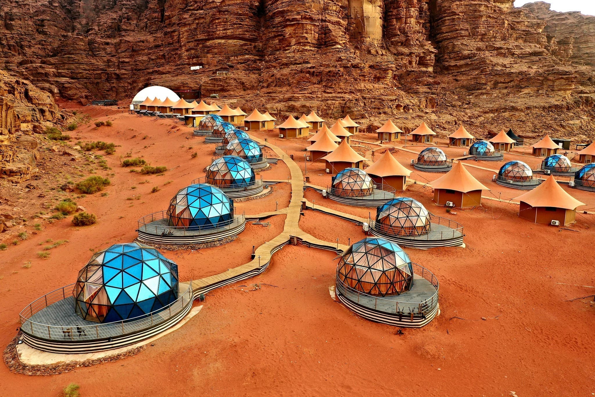 Transparent luxury dome at Memories Aicha Luxury Camp overlooking the red dunes of Wadi Rum at sunset.