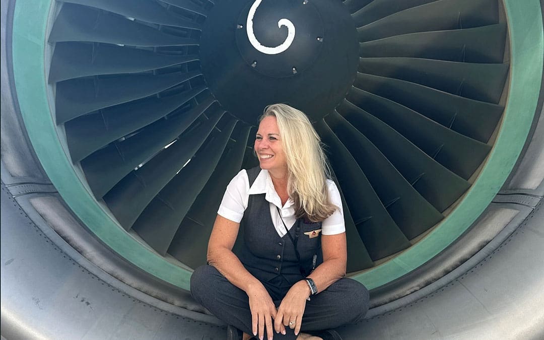 SherryMartinPeters _1080x675 Image of flight attendant, Sherry Martin Peters, sitting inside of an airplane engine. The blog is about learning to pack like a flight attendant.