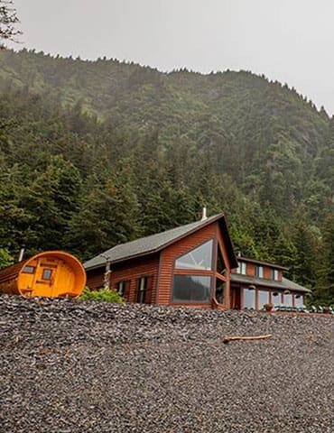 Ocean-view cabin at Kenai Fjords Wilderness Lodge overlooking Resurrection Bay, surrounded by spruce forest and glaciers.